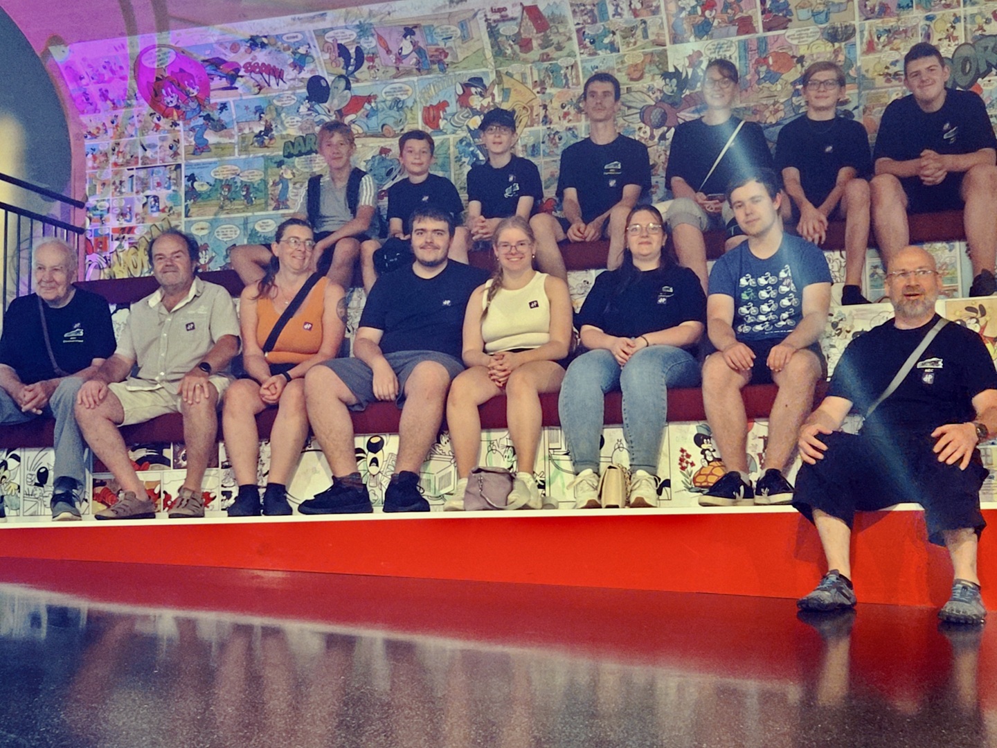 Gruppenfoto auf der Tribüne, im Hintergrund zahlreiche Zeichnungen zum Ausstellungsthema Fix und Foxy